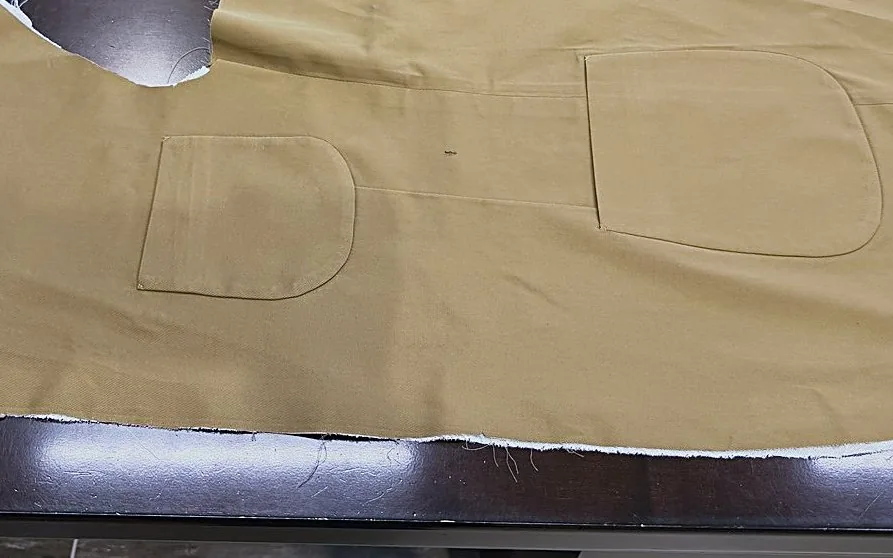 Cut tan cloth pieces laid out on the dark cutting table
