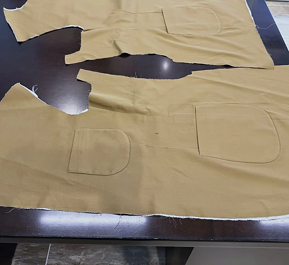 Cut tan cloth pieces laid out on the dark cutting table