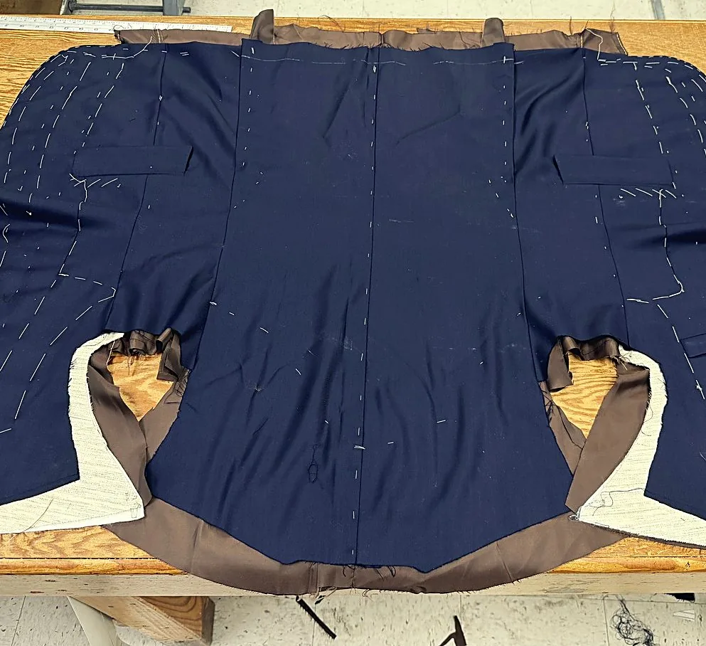 Navy jacket body laid flat on the table, both armholes, basting