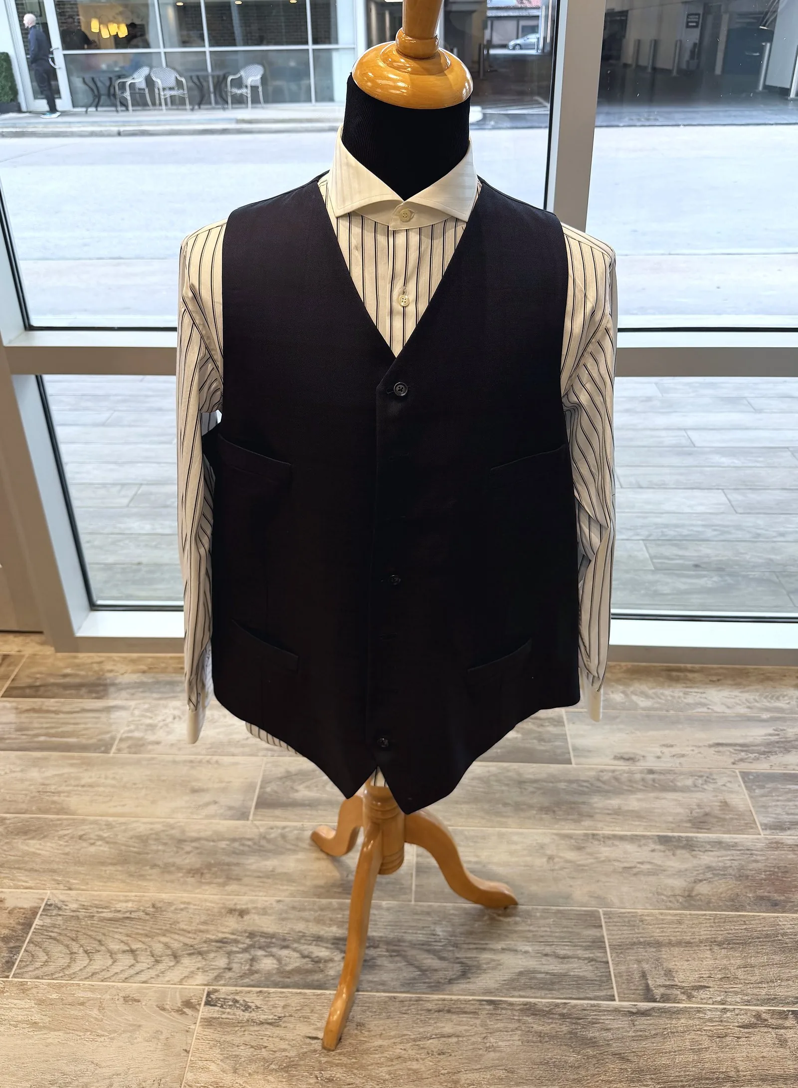 A black waistcoat buttoned over a cream striped shirt on the shop's form